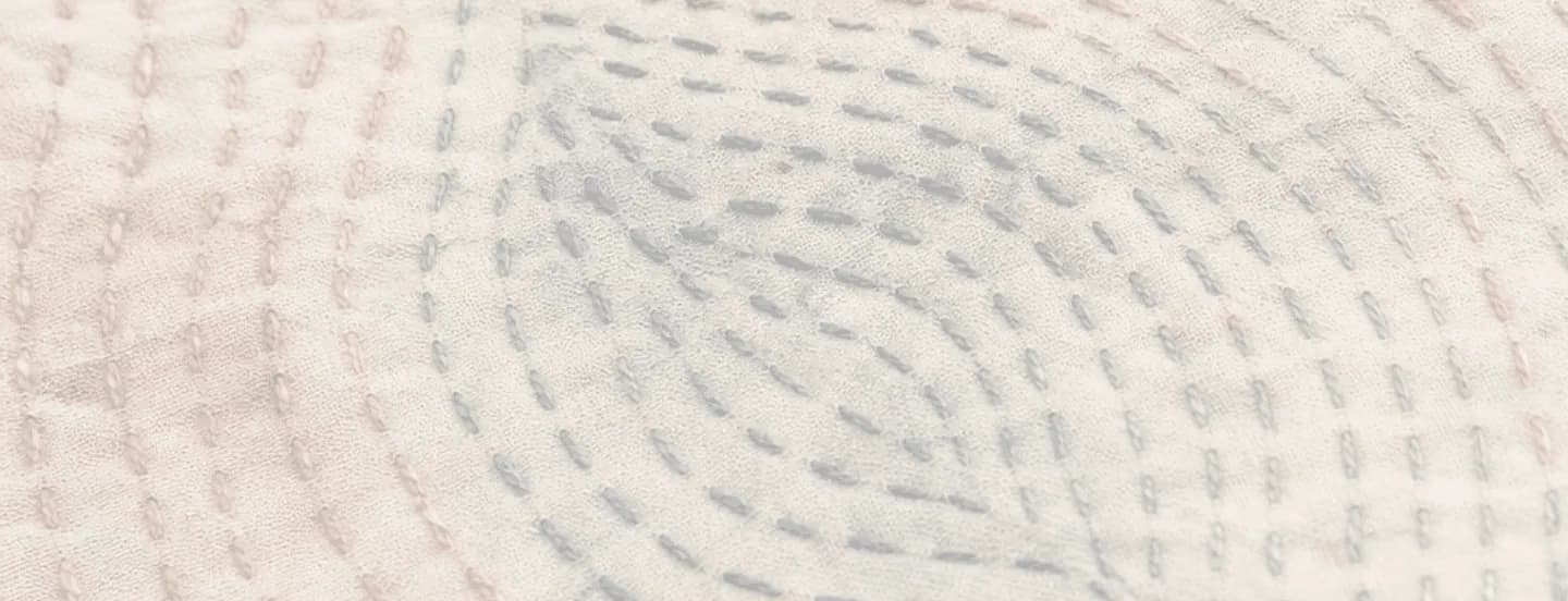 Cream quilted textile with rows of pale blue running stitches