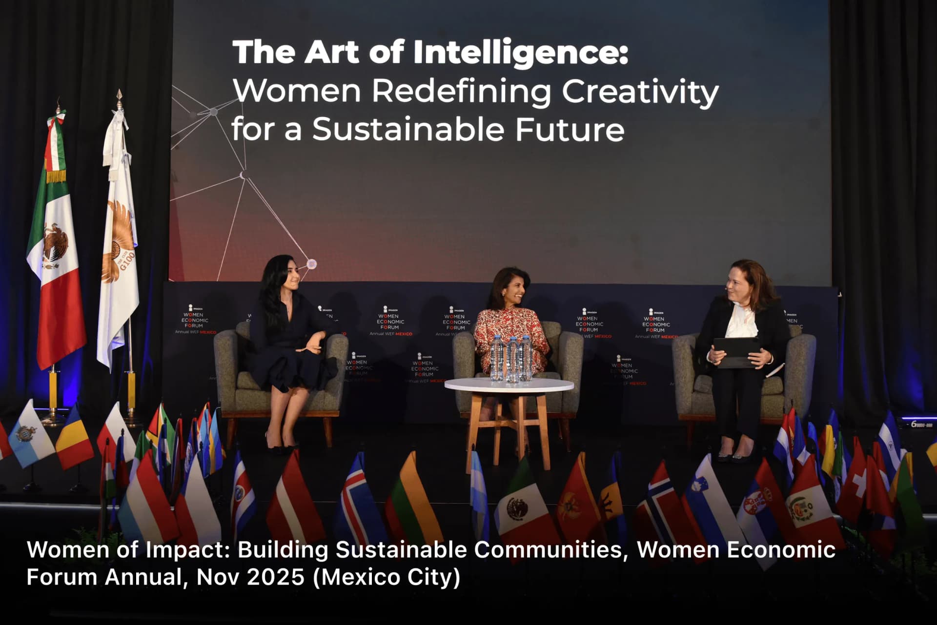 Three panellists on stage in front of a row of national flags at the Women Economic Forum Annual, Mexico City, November 2025 — Women of Impact: Building Sustainable Communities